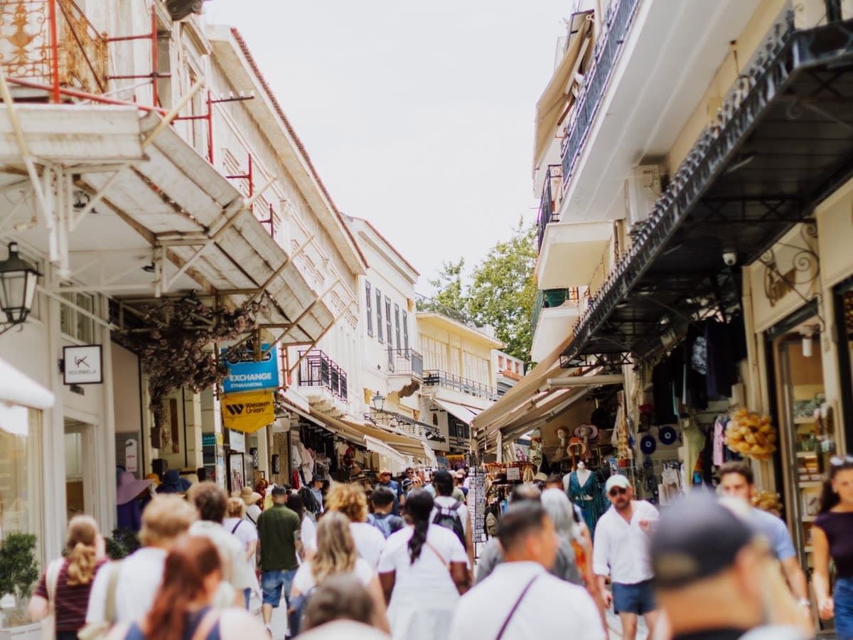 Επισκέπτες περπατούν σε μαρμάρινο δρόμο στην Πλάκα, κάτω από την Ακρόπολη